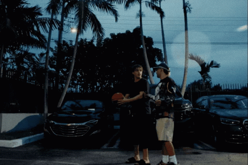 Two Men Standing In A Parking Lot Holding A Basketball GIF