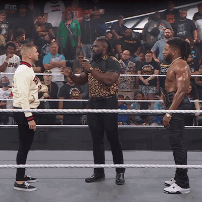 Two Men Standing In A Wrestling Ring With One Wearing A Sweater That Says Japan GIF