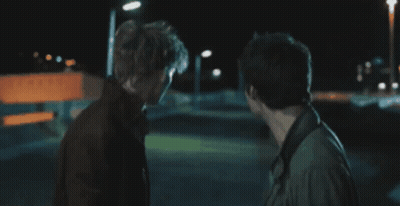 Two Men Standing In Dark Room GIF
