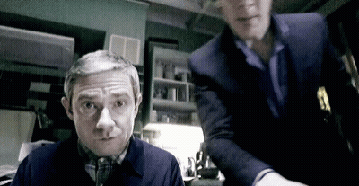 Two Men Standing In Dark Room One Looking At Camera GIF