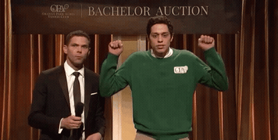 Two Men Standing In Front Of A Bachelor Auction Banner GIF