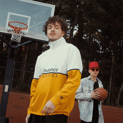 Two Men Standing In Front Of A Basketball Hoop Wearing New Balance Athletics Shirts GIF