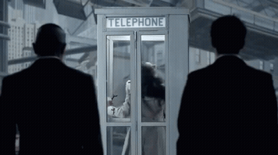 Two Men Standing In Front Of A Telephone Booth With A Woman Inside GIF