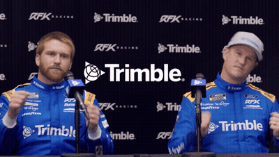 Two Men Standing In Front Of A Trimble Banner GIF