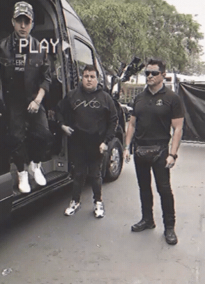 Two Men Standing In Front Of A Van With The Word Play On The Screen GIF