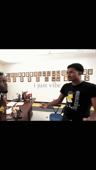 Two Men Standing In Front Of A Wall That Says I Just Vibe On It GIF