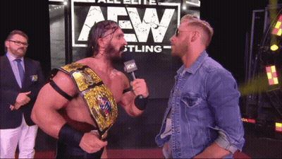 Two Men Standing In Front Of AEW Sign GIF