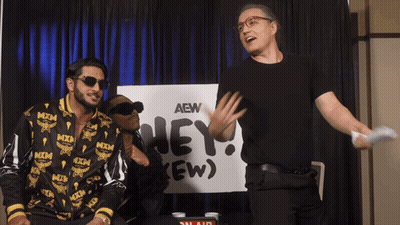 Two Men Standing In Front Of AEW Sign GIF