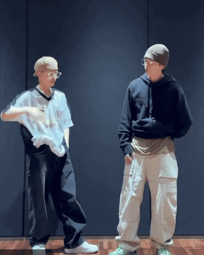 Two Men Standing In Front Of Black Wall GIF