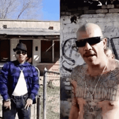 Two Men Standing In Front Of Brick Building GIF