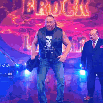 Two Men Standing In Front Of Brock Sign GIF
