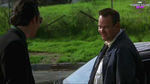 Two Men Standing In Front Of Car With Vox Video Club GIF