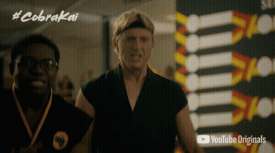 Two Men Standing In Front Of Cobra Kai Sign GIF