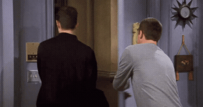 Two Men Standing In Front Of Door With Clock GIF