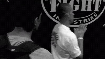 Two Men Standing In Front Of Fight Industries Sign GIF