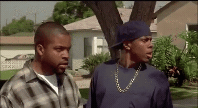 Two Men Standing In Front Of House One In Blue Hat GIF