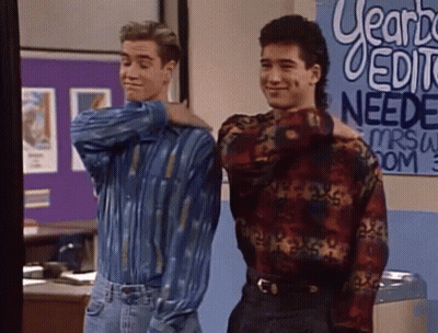 Two Men Standing In Front Of Learn Needs Sign GIF