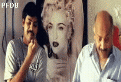 Two Men Standing In Front Of Madonna Painting GIF