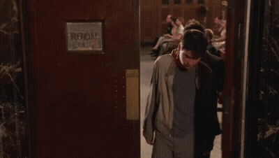 Two Men Standing In Front Of Room Sign GIF