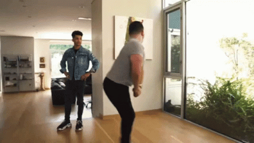 Two Men Standing In Living Room With Large Window GIF