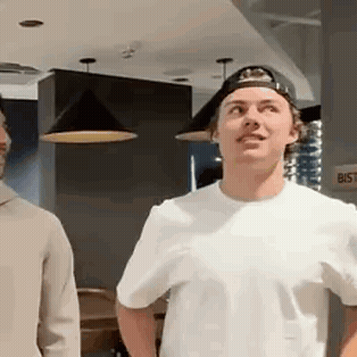 Two Men Standing In Room One Wearing Cap GIF