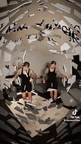 Two Men Standing In Room With Ceiling Fan And Clock GIF