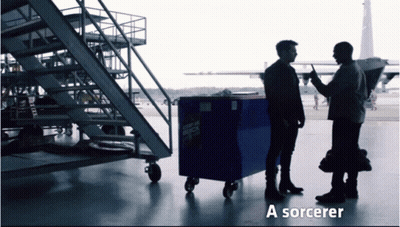 Two Men Standing Next To A Blue Box That Says ' A Sorcerer ' On The Bottom GIF