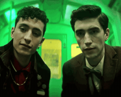Two Men Standing Next to Each Other Green Background
