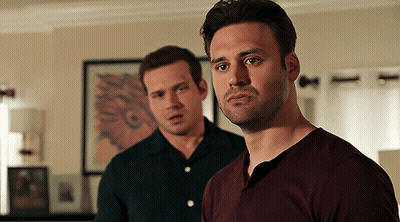 Two Men Standing Next To Each Other In A Living Room Looking At The Camera GIF