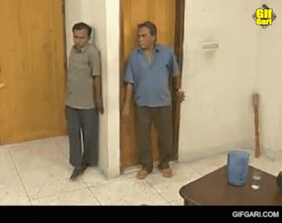 Two Men Standing Next To Each Other In A Room GIF