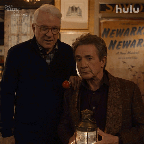 Two Men Standing Next To Each Other In Front Of A Sign That Says Newark Newark GIF