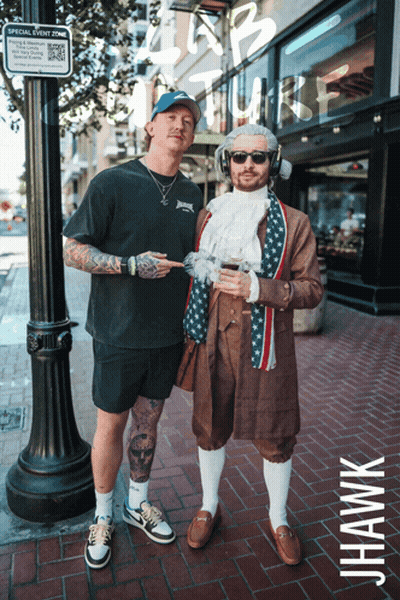 Two Men Standing Next To Each Other In Front Of A Sign That Says Special Event Zone On It GIF