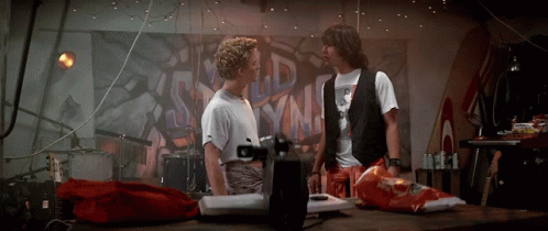 Two Men Standing Next To Each Other In Front Of A Wall With Graffiti That Says ' Old ' On It GIF