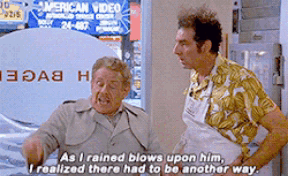 Two Men Standing Next To Each Other In Front Of An American Video Sign GIF