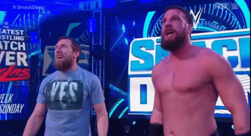 Two Men Standing Next To Each Other In Front Of Smackdown Sign GIF