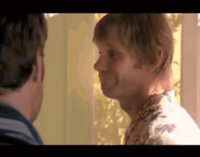 Two Men Standing Next To Each Other Looking At Each Other One In Hawaiian Shirt GIF