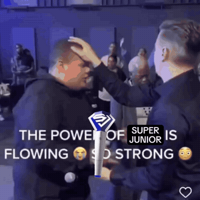 Two Men Standing Next To Each Other One Holding Super Junior Stick GIF
