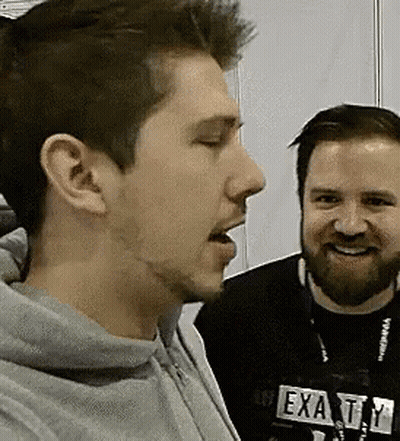 Two Men Standing Next To Each Other One In Exatty Hoodie GIF