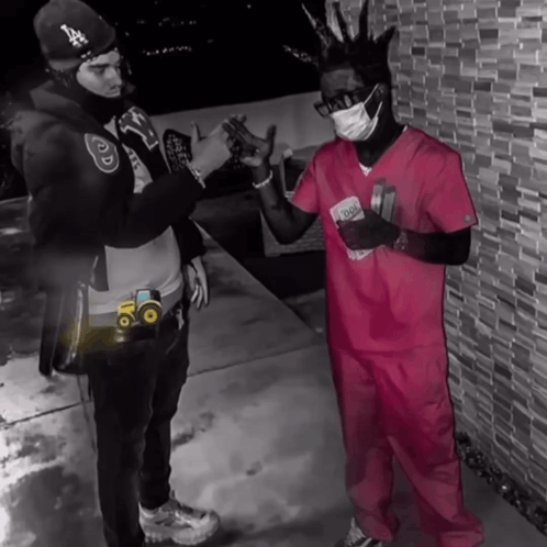 Two Men Standing Next To Each Other One Wearing A Pink Scrub Top And The Other Wearing A Mask GIF