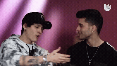 Two Men Standing Next To Each Other With Cross Necklace GIF