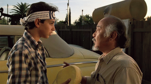 Two Men Standing Next To Each Other With One Wearing A Headband That Says Karate GIF