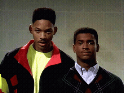Two Men Standing Next To Each Other With One Wearing A Sweater GIF