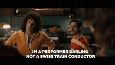 Two Men Standing Next To Each Other With The Words Im A Performer Darling Not A Swiss Train Conductor Written Below Them GIF