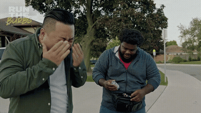 Two Men Standing On A Sidewalk With The Words Run The Burbs On The Bottom Right GIF
