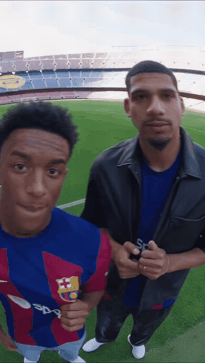 Two Men Standing On A Soccer Field With One Wearing A Shirt That Says Sport GIF