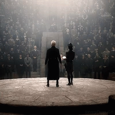 Two Men Standing On A Stage Holding Hands In Front Of A Large Crowd GIF