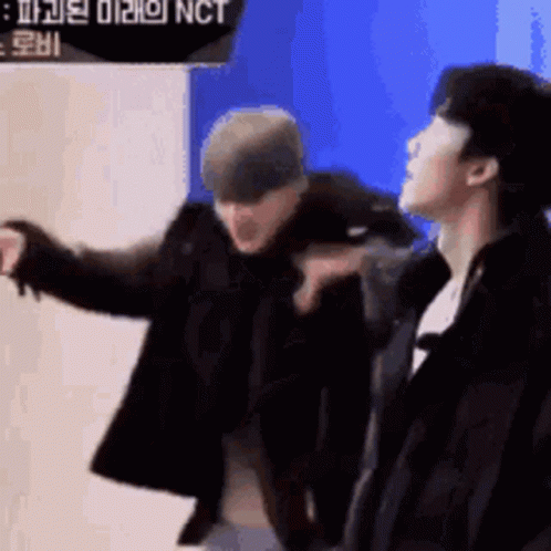 Two Men Standing, One Pointing At Camera GIF