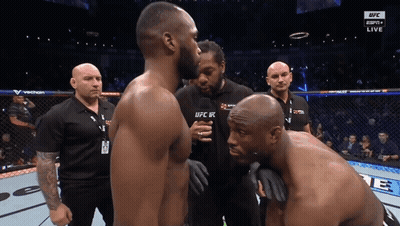 Two Men Standing, One Wearing UFC Shirt GIF
