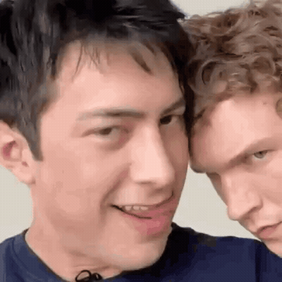 Two Men Standing Together One Smiling GIF