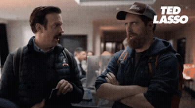Two Men Standing With Ted Lasso Logo GIF